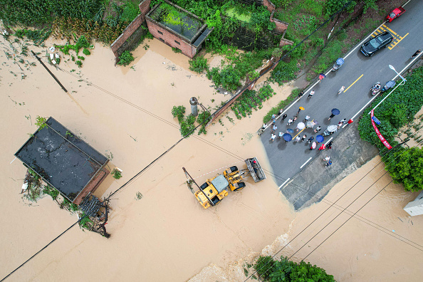 Des résidents locaux évacués par une chargeuse sur roues dans une zone inondée après des tempêtes de pluie à Dianjiang, le 11 juillet. Illustration. (STR/AFP via Getty Images)