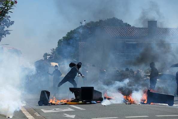 Un manifestant jette une bombe lacrymogène lancée par un gendarme à La Rochelle, le 20 juillet 2024. (ROMAIN PERROCHEAU/AFP via Getty Images)