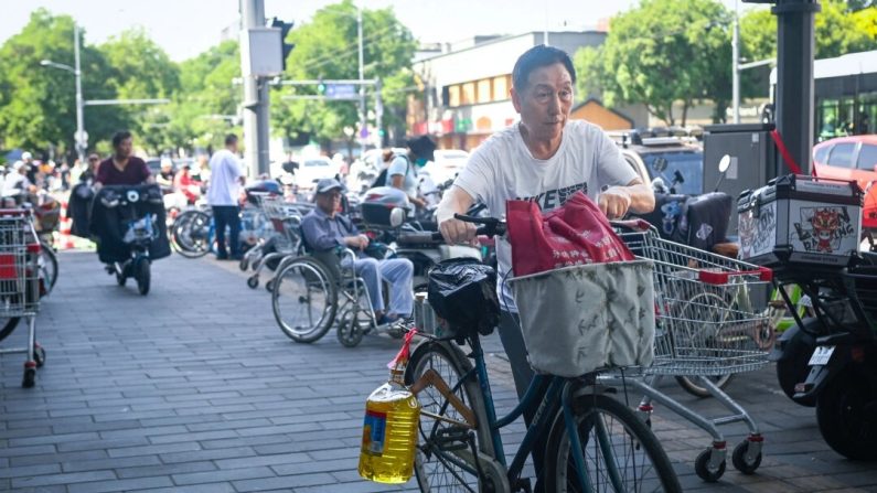 Un homme à vélo transporte un baril d'huile de cuisine à la sortie d'un supermarché à Pékin, le 12 juin 2024. (Wang Zhao/AFP via Getty Images)