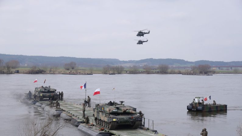 Des hélicoptères des forces armées polonaises survolent des chars Leopard 2PL polonais qui traversent la Vistule sur un ferry militaire français lors de l'exercice militaire Dragon 24 de l'OTAN, le 4 mars 2024, près de Gniew, en Pologne. (Sean Gallup/Getty Images)