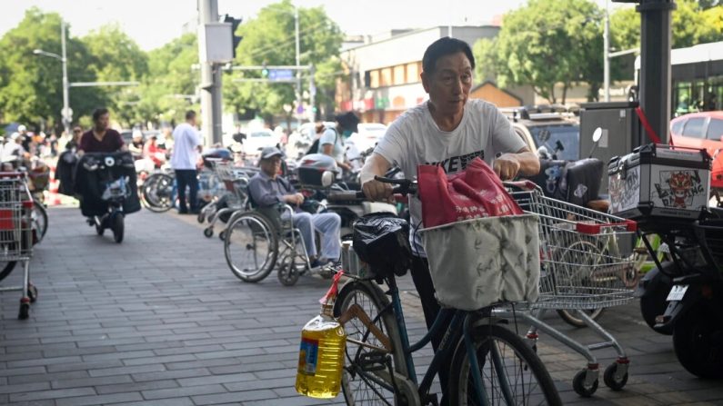 Un homme à vélo avec un baril d'huile de cuisine quitte un supermarché à Pékin le 12 juin 2024. (Wang Zhao/AFP via Getty Images)