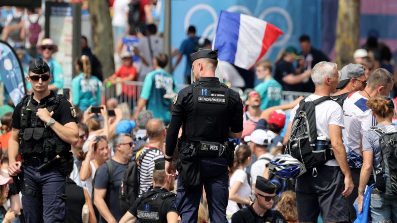 Des gendarmes français regardent les spectateurs suivre la progression des athlètes lors du programme de triathlon des Jeux olympiques de Paris, le 31 juillet 2024. (Photo : LUDOVIC MARIN/AFP via Getty Images)