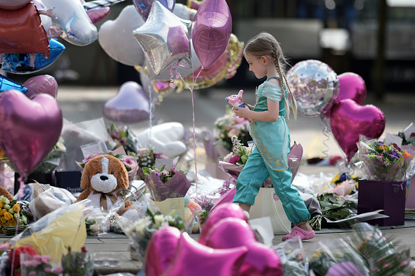 Une jeune fille se recueille parmi les milliers de fleurs et d'hommages déposés devant le Centre d'art Atkinson le 31 juillet 2024 à Southport, en Angleterre. (Christopher Furlong/Getty Images)