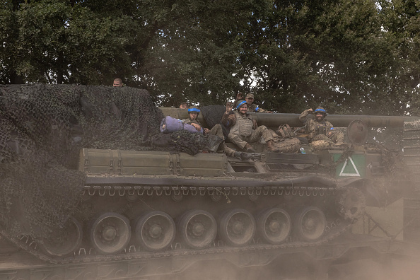 Des militaires ukrainiens sont assis sur une pièce d'artillerie automotrice 2S7 Pion transportée par un camion militaire, dans la région de Sumy, près de la frontière avec la Russie, le 11 août 2024, dans le contexte de l'invasion russe de l'Ukraine. (Photo ROMAN PILIPEY/AFP via Getty Images)