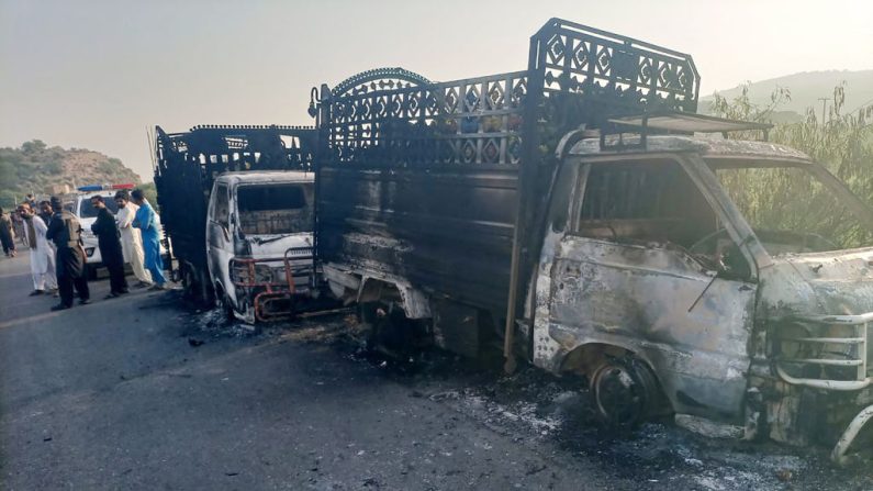 Le personnel de sécurité se tient près des véhicules carbonisés sur le site de la fusillade situé sur la route nationale dans le district de Musakhail, dans la province du Baloutchistan, le 26 août 2024. (STR/AFP via Getty Images)