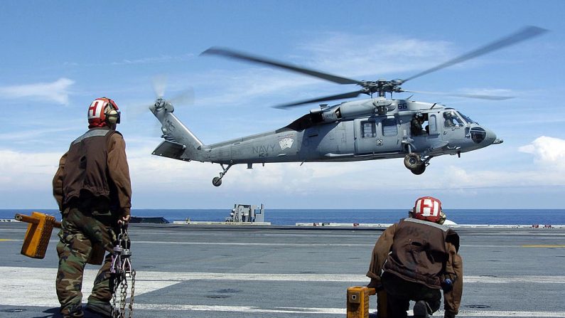 Le personnel de la division de ligne se prépare à caler et enchaîner un MH-60S Knighthawk, avant son atterrissage sur le pont d'envol à bord de l'USS Abraham Lincoln. (Tyler J. Clements/U.S. Navy via Getty Images)