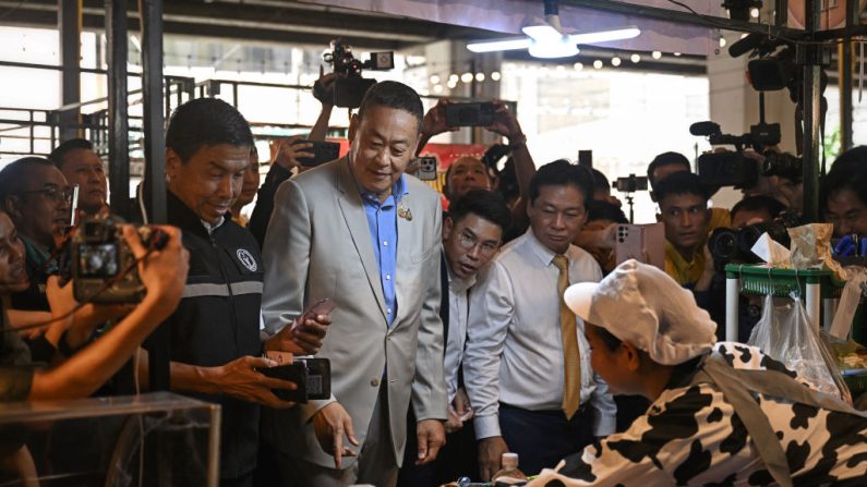 Le gouverneur de Bangkok Chadchart Sittipunt (au centre à gauche) achète de la nourriture pour le Premier ministre thaïlandais Srettha Thavisin (à dr.) alors qu'ils visitent un marché alimentaire à Bangkok, le 14 août 2024. (LILLIAN SUWANRUMPHA/AFP via Getty Images)