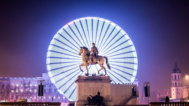 Une statue de Louis XIV avec une grande roue en arrière-plan, pendant la Fête des Lumières à Lyon, en France. (Yanis Ourabah/Getty Images)