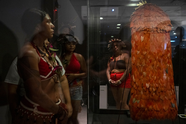 Des membres du peuple indigène Tupinamba devant le manteau Tupinamba restitué par le Musée national du Danemark, dans le parc Quinta de Boa Vista à Rio de Janeiro au Brésil, le 11 septembre 2024. (Photo PABLO PORCIUNCULA/AFP via Getty Images)