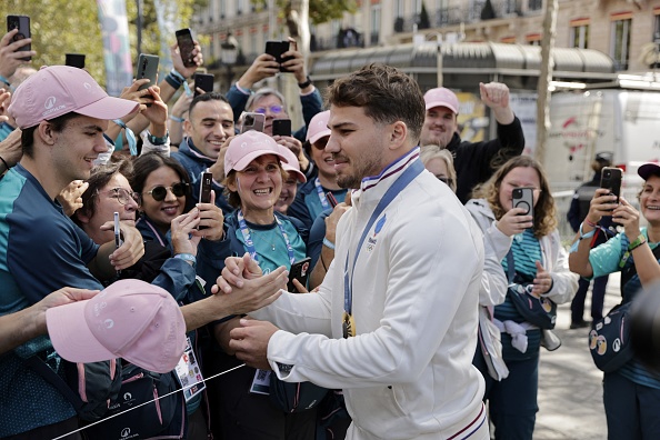 Antoine Dupont (au c.), médaillé d'or en rugby à 7, salue la foule lors du défilé des athlètes ayant participé aux Jeux olympiques et paralympiques de Paris 2024 sur l'avenue des Champs-Élysées. (ANDRE PAIN/POOL/AFP via Getty Images)