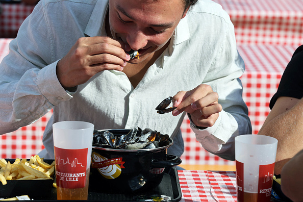 Un homme mange un plat de moules-frites lors du marché aux puces annuel de la Braderie de Lille à Lille, le 14 septembre 2024. (FRANCK CRUSIAUX/AFP via Getty Images)