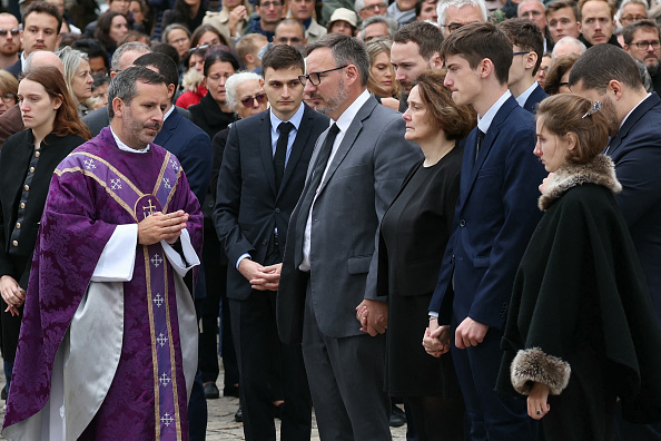 Un prêtre s'approche des proches de Philippine Le Noir de Carlan, la jeune étudiante de Paris-Dauphine retrouvée morte dans le bois de Boulogne samedi 21 septembre 2024, avant la cérémonie funéraire devant la cathédrale de Versailles, le 27 septembre 2024.   (ALAIN JOCARD/AFP via Getty Images)