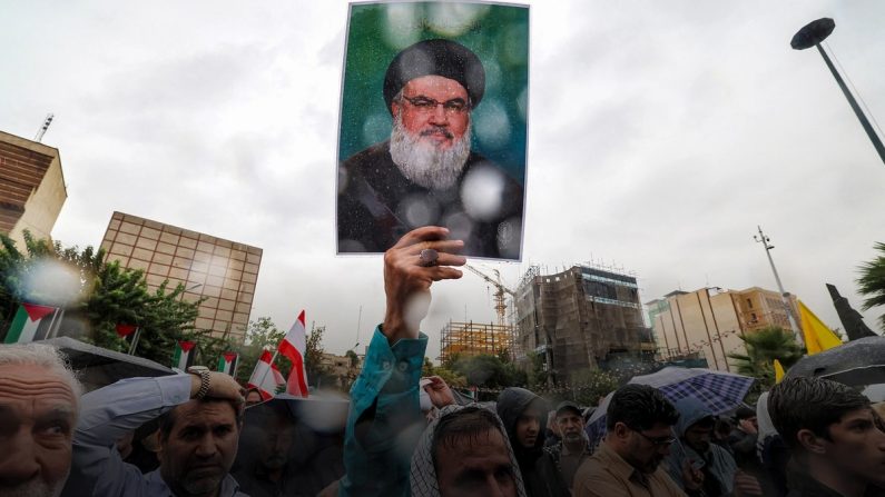 Un manifestant se tient sous la pluie en brandissant une photo du chef du Hezbollah libanais Hassan Nasrallah, tué la veille par une frappe aérienne israélienne, lors d'une manifestation anti-israélienne sur la place de la Palestine à Téhéran, en Iran, le 28 septembre 2024. (Atta Kenare/AFP via Getty Images)