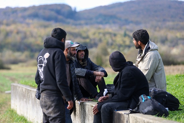 Des migrants sont assis sur un mur dans le village de Trzac, près de Bihac, où de nombreux migrants arrivent après avoir été repoussés de l'autre côté de la rivière Korana par la police croate, le 8 novembre 2023. (DAMIR SENCAR/AFP via Getty Images)