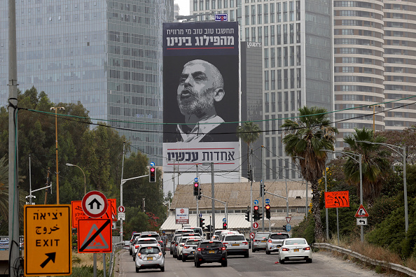 Des voitures passent devant un panneau d'affichage portant une inscription en hébreu disant « pensez bien à qui profite notre division - l'unité maintenant », avec un portrait du chef de l'aile politique de l’organisation terroriste palestinienne Hamas dans la bande de Gaza Yahya Sinwar, à Tel Aviv le 26 avril 2024. (Photo JACK GUEZ/AFP via Getty Images)