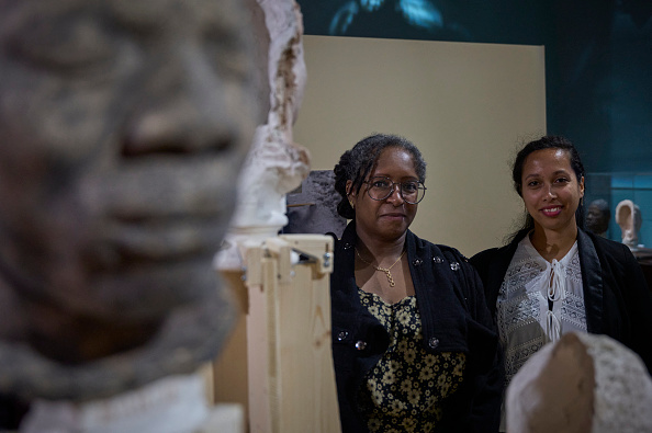 Doris Lily (C) et Clarisse Lily, descendantes d'un captif africain, posent lors de l'exposition « Visages d'ancêtres » au château de Blois. Depuis 1940, le château royal de Blois abrite dans ses réserves une collection de 53 bustes moulés à partir d'anciens captifs africains, dont la plupart ont été réduits en esclavage à l'île Maurice. Cette collection a été rassemblée sur l'île en 1846 par Eugène de Froberville dans le cadre de son « enquête ethnologique » sur l'Afrique de l'Est. (Photo GUILLAUME SOUVANT/AFP via Getty Images)
