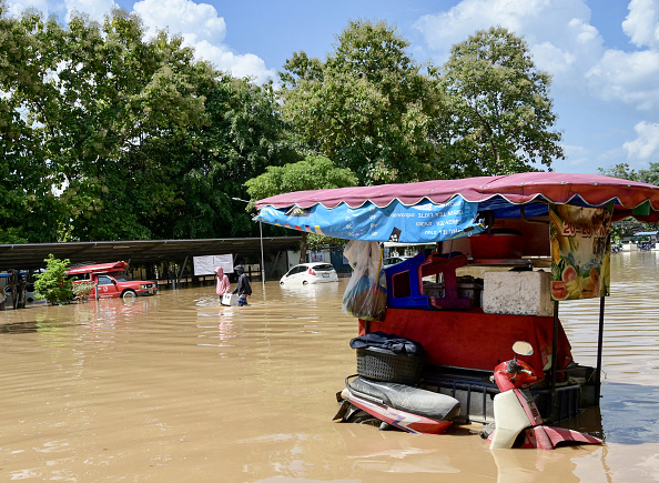 Des habitants pataugent dans une rue inondée à Chiang Mai, le 6 octobre 2024. (STR/AFP via Getty Images)