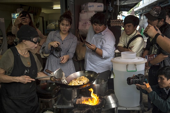 Jay Fai (à g.) réputée pour ses omelettes au crabe et ses currys, dispose d'une cuisine en plein air. (LILLIAN SUWANRUMPHA/AFP via Getty Images)