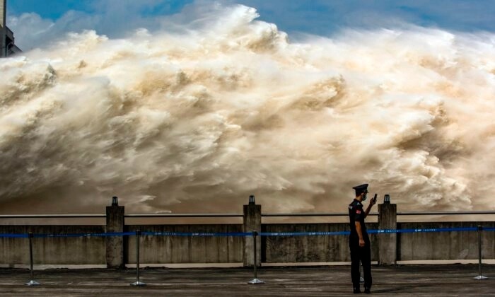 Un agent de sécurité regarde son smartphone pendant que l'eau est libérée du barrage des Trois Gorges, un gigantesque projet hydroélectrique sur le fleuve Yangtze, pour soulager la pression des inondations à Yichang, dans la province de Hubei, en Chine, le 19 juillet 2020. (STR/AFP via Getty Images)