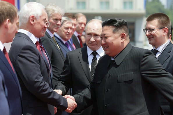 Sur cette photo de famille diffusée par l'agence d'État russe Sputnik, le président russe Vladimir Poutine (C) observe le ministre russe de la Défense Andrei Belousov (2e à gauche) serrer la main du dirigeant nord-coréen Kim Jong Un lors d'une cérémonie de bienvenue sur la place Kim Il Sung à Pyongyang, le 19 juin 2024. (Photo GAVRIIL GRIGOROV/POOL/AFP via Getty Images)