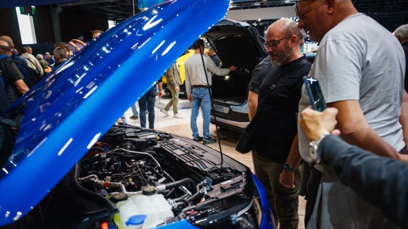 Des visiteurs regardent le moteur hybride de la voiture Ford Puma présentée au Mondial de l'Automobile de Paris à Paris Expo, Porte de Versailles à Paris, le 15 octobre 2024. (DIMITAR DILKOFF/AFP via Getty Images)