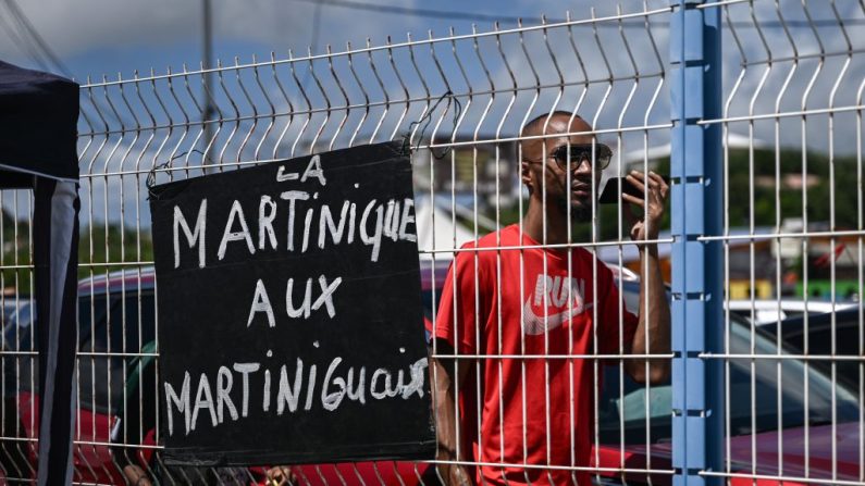 Un partisan du RPPRAC (Rassemblement pour la protection des peuples et des ressources afro-caribéennes) passe devant une pancarte sur laquelle on peut lire « La Martinique aux Martiniquais » lors d'un rassemblement pour des discussions sur la lutte contre la vie chère, à Fort-de-France, sur l'île française des Caraïbes de la Martinique, le 19 octobre 2024.(PHILIPPE LOPEZ/AFP via Getty Images)