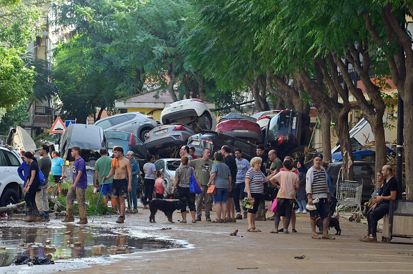 Des habitants se rassemblent dans la rue à côté d'une pile de voitures le 31 octobre 2024 après les inondations soudaines qui ont touché la ville de Massanassa, dans la région de Valence, à l'est de l'Espagne. (JOSE JORDAN/AFP via Getty Images)