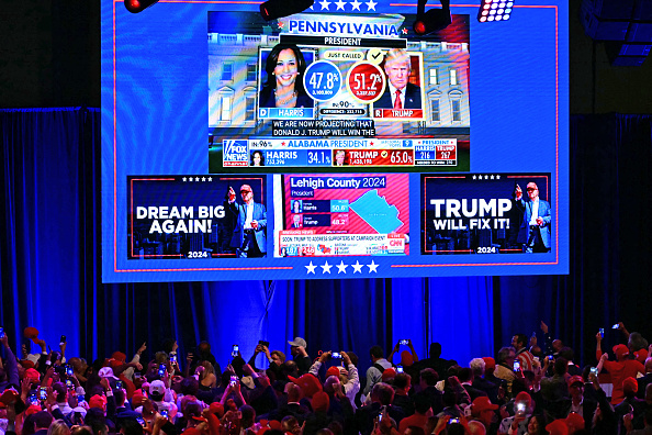 Des partisans de Donald Trump prennent des photos d'un écran au West Palm Beach Convention Center à West Palm Beach, en Floride, le 6 novembre 2024. (JIM WATSON/AFP via Getty Images)