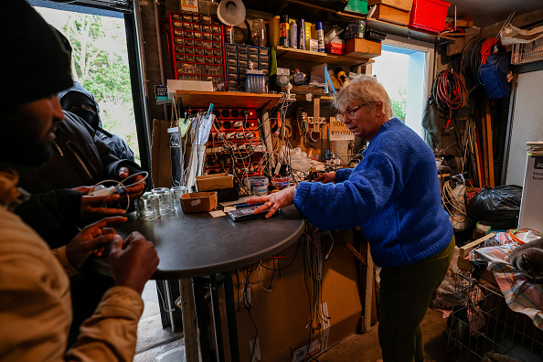 Brigitte Lips, surnommée Mamie Charge, enregistre les téléphones des migrants à recharger dans son garage de Calais, le 26 novembre 2024. (DENIS CHARLET/AFP via Getty Images)