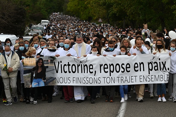 Des personnes tiennent une banderole en mémoire de Victorine Dartois lors d'une marche blanche à Villefontaine, en 2020. (JEAN-PHILIPPE KSIAZEK/AFP via Getty Images)