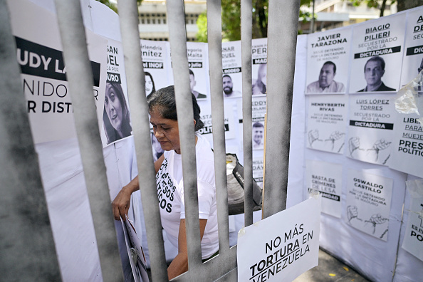 Une femme colle une affiche dans une fausse cellule de prison pour protester contre le gouvernement du président Nicolas Maduro et exiger la liberté des prisonniers politiques lors d'une manifestation devant l'ambassade du Brésil à Caracas, le 11 septembre 2024. JUAN BARRETO/AFP via Getty Images)