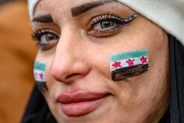 Une femme portant des drapeaux syriens sur les joues regarde les résidents syriens en Turquie célébrer la fin du régime Baas en Syrie après que les combattants rebelles ont pris le contrôle de Damas pendant la nuit, à la mosquée Fatih, à Istanbul, le 8 décembre 2024. (Photo YASIN AKGUL/AFP via Getty Images)