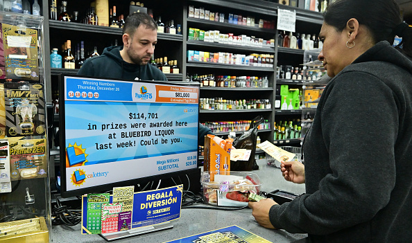 Une personne achète son billet de loterie Mega Millions dans un magasin d'alcool où des billets gagnants ont été vendus, le 27 décembre 2024 à Hawthorne en Californie. (Photo FREDERIC J. BROWN/AFP via Getty Images)