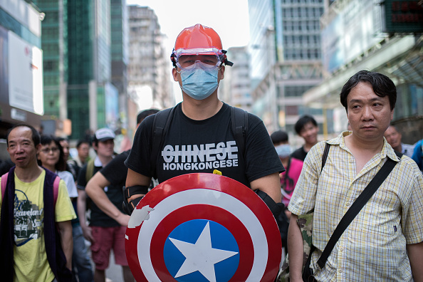 Un homme portant un équipement de protection et un bouclier de la série de bandes dessinées « Captain America » monte la garde à côté d'une barricade de protestation pro-démocratie dans le quartier de Mongkok à Hong Kong le 19 octobre 2014.  La police de Hong Kong a affronté les manifestants, le gouvernement a déclaré que 20 personnes ont été blessées dans une quatrième nuit de violence après près de trois semaines de rassemblements largement pacifiques en faveur de la démocratie.  (ALEX OGLE/AFP via Getty Images)