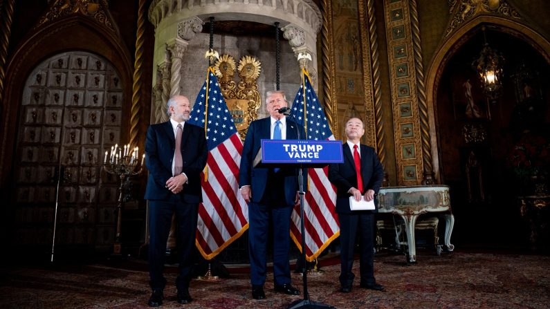 Le président élu Donald Trump, accompagné du PDG de SoftBank Masayoshi Son (à dr.) et du PDG de Cantor, Fitzgerald Howard Lutnick, qu'il a choisi pour le poste de secrétaire au Commerce, s'exprime lors d'une conférence de presse dans sa propriété de Mar-a-Lago à Palm Beach (Floride), le 16 décembre 2024. (Andrew Harnik/Getty Images)