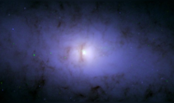 Image du télescope Hubble montrant le noyau de la galaxie NGC 5084. Une ligne noire verticale près du centre illustre la courbure d'un disque poussiéreux en orbite autour du noyau, suggérant la présence d'un trou noir supermassif à l'intérieur. (Image : NASA)